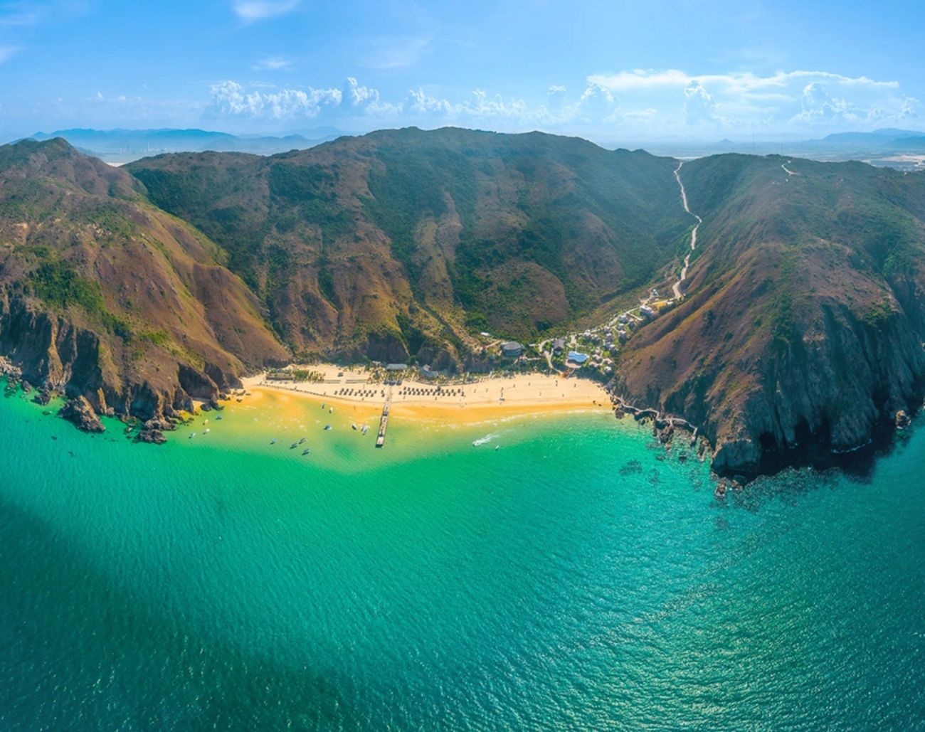 Khung cảnh toàn diện của bãi tắm Kỳ Co Quy Nhơn với nước biển xanh ngọc và bãi cát cong ôm núi, nơi lý tưởng để check-in và nghỉ dưỡng.